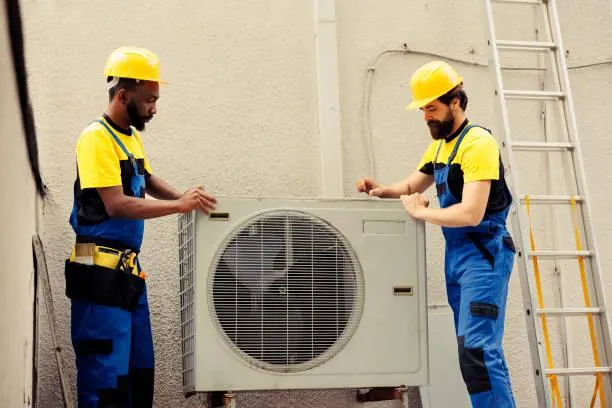 Two technicians servicing an outdoor air conditioning unit